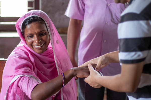 A woman smiles while her hand is examined for signs of leprosy. Photo credit: Andie Tucker