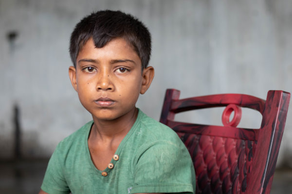 A Nepalese boy in a great shirt sits in a red chair. Photo credit: Andie Tucker