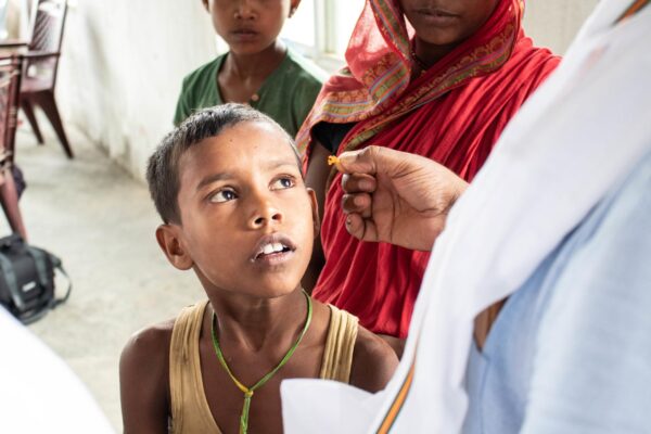 A doctor holds a flower petal up to a boy's face to check for sensitivity. Photo Credit: Andie Tucker